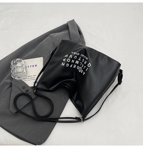 Detail of black PU leather tote with white alphabet print and adjustable shoulder strap