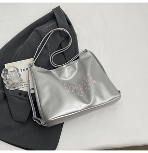 Silver metallic tote bag with pink typography detail shown on professional aesthetic layout