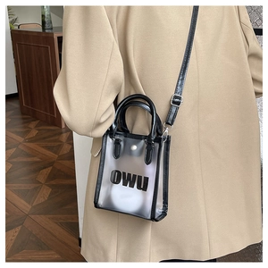 Detail of transparent PVC jelly bag with OWU lettering and black shoulder strap for summer