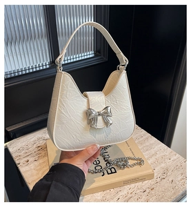 Détail du sac plissé blanc crème avec nœud argenté et bandoulière chaîne