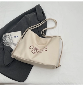 Flat lay of cream oversized tote bag with letter print and brown shoulder straps