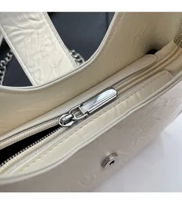 Détail de la fermeture éclair argentée et de la texture plissée du sac sous l'aisselle