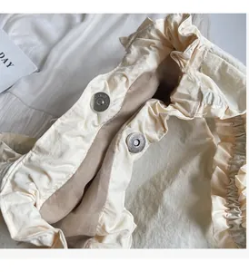 Detail view of beige ruffled canvas tote bag featuring secure silver magnetic snap closures