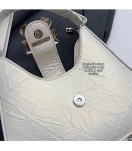 Détail du sac en cuir plissé blanc avec boucle magnétique argentée et chaîne