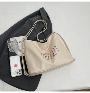 Detailed view of beige large tote bag with red lettering on a grey business suit