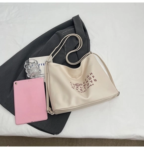 Detail of off-white faux leather tote bag with red circular print on a grey blazer