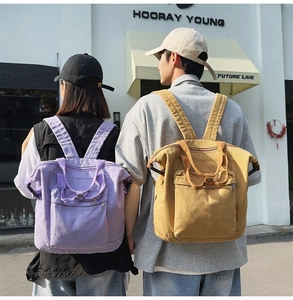 Outdoor view of two models wearing durable canvas backpacks in purple and yellow colors