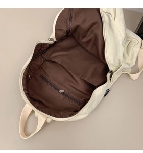 Internal view of a spacious canvas backpack showing brown lining and zippered inner pocket