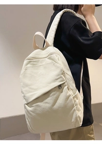 Side view of white canvas backpack on model with wide straps and spacious pockets