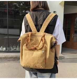 Close-up of a khaki canvas tote backpack featuring adjustable buckles and smooth metal zippers