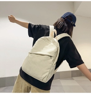 Close-up of off-white canvas backpack showing side pocket and natural fabric texture