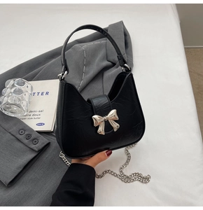 Détail du sac demi-lune noir avec nœud métallique et bandoulière chaîne argentée