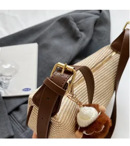 Détail du sac en paille tissée avec bandoulière en cuir marron et boucle dorée