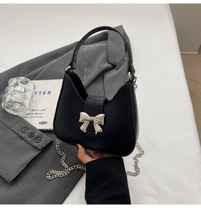Détail du sac hobo noir avec nœud argenté et bandoulière en chaîne métallique