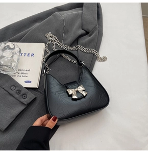 Détail du sac bandoulière en cuir plissé noir avec nœud argenté et bandoulière chaîne