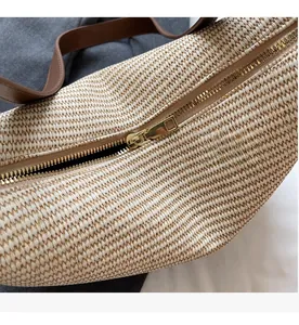 Gros plan sur la fermeture éclair dorée et la texture tissée du sac bandoulière beige