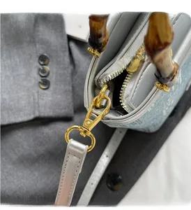 Detail of luxury bamboo handle and polished gold metal hardware on denim bucket bag