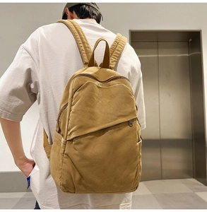 Close-up of mustard yellow canvas backpack featuring a diagonal zipper pocket and wide straps