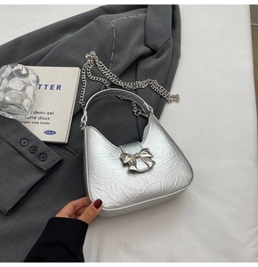 Vue détaillée du sac hobo argenté avec plis métalliques et boucle en forme de nœud
