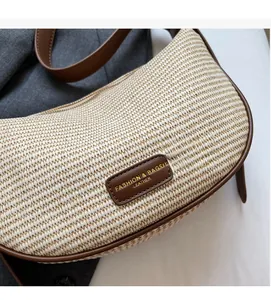 Détail du sac demi-lune en fibre tressée crème avec garniture en cuir brun et logo