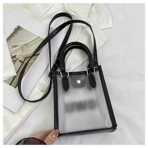 Close-up of clear PVC jelly bag with black trim, metal clasp and adjustable strap