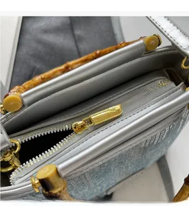 Detail of bamboo handle and gold zipper on light blue denim texture bucket bag