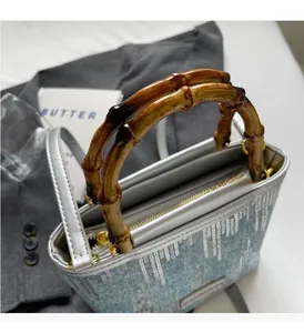 Detail of blue textured bucket bag with bamboo handles and metallic zipper closure