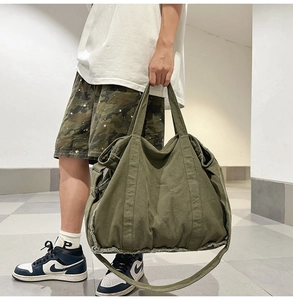Detail of army green canvas tote bag with distressed frayed edges and double handles