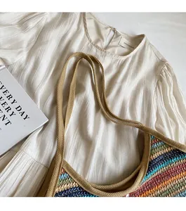 Detail of colorful striped straw tote with comfortable woven shoulder straps and hand texture