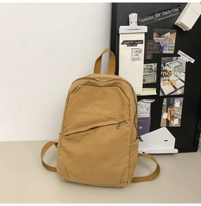 Detail view of ginger yellow canvas backpack with side pockets and front zipper