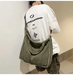 Detail of army green canvas tote bag showing frayed edges and adjustable shoulder strap