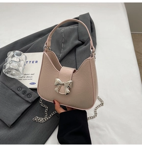 Détail du mini sac rose clair avec texture plissée et ornement de nœud argenté