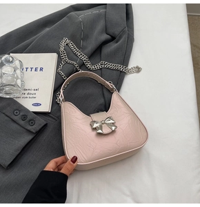 Détail du sac bandoulière rose clair avec texture plissée et nœud argenté