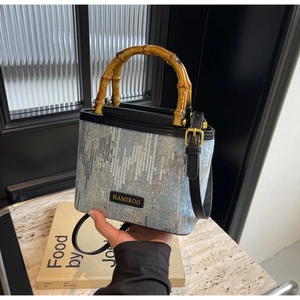 Detail of blue denim bucket bag with silver sequins and round wooden bamboo handle
