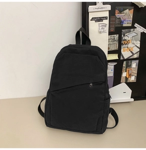 Detail of minimalist black canvas backpack with asymmetrical pocket and side mesh holder
