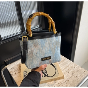 Close-up of denim bucket bag featuring a natural bamboo handle and silver sequins