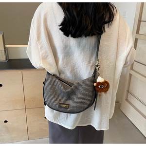 Detail of woven crescent hobo bag with adjustable strap and plush bear charm