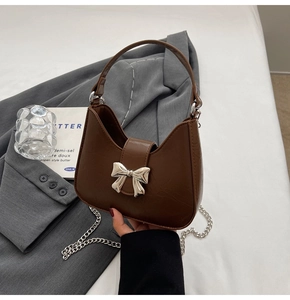 Détail d'un sac demi-lune marron foncé avec nœud argenté et bandoulière
