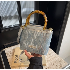 Close-up of blue denim bucket bag with silver sequins and unique bamboo handle