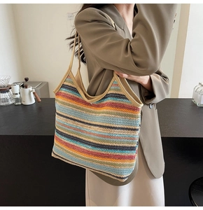 Close-up of a large woven straw tote bag with multi-color stripes and a metal buckle clasp