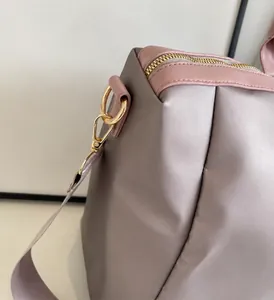 Detail of light gold hardware and glossy lavender fabric on a travel bag