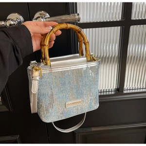 Detail showing vintage bamboo handle and sparkling sequin denim texture on a bucket bag