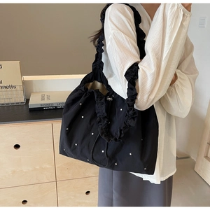 Detail of black pleated tote bag with silver studs and ruffled shoulder strap
