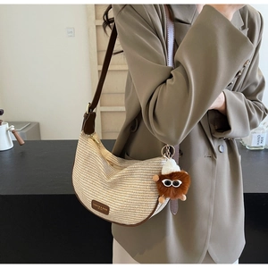 Detail of striped woven crescent bag featuring a funny plush charm with sunglasses