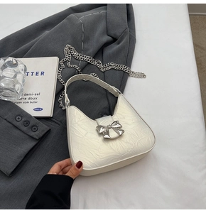 Détail du sac à bandoulière plissé blanc crème avec boucle nœud argenté et chaîne en métal