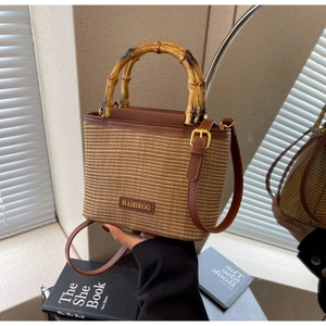Detail of woven straw bucket bag featuring bamboo handle and leather trim in natural light