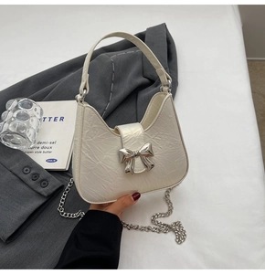 Détail du sac sous le bras plissé blanc avec nœud argenté et chaîne en métal