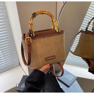 Detail of woven bucket bag featuring natural bamboo handle and brown leather trim accents