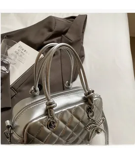 Detail of silver metallic quilted handbag with braided handle and bow charm