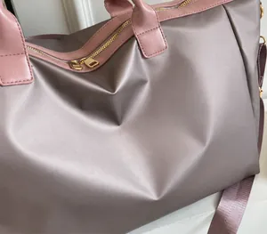 Detailed macro of silver glossy fabric and pink leather trim on travel bag with gold zipper